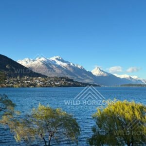 Still lake waters beneath snow-lined alpine ridges. Frankton, New Zealand