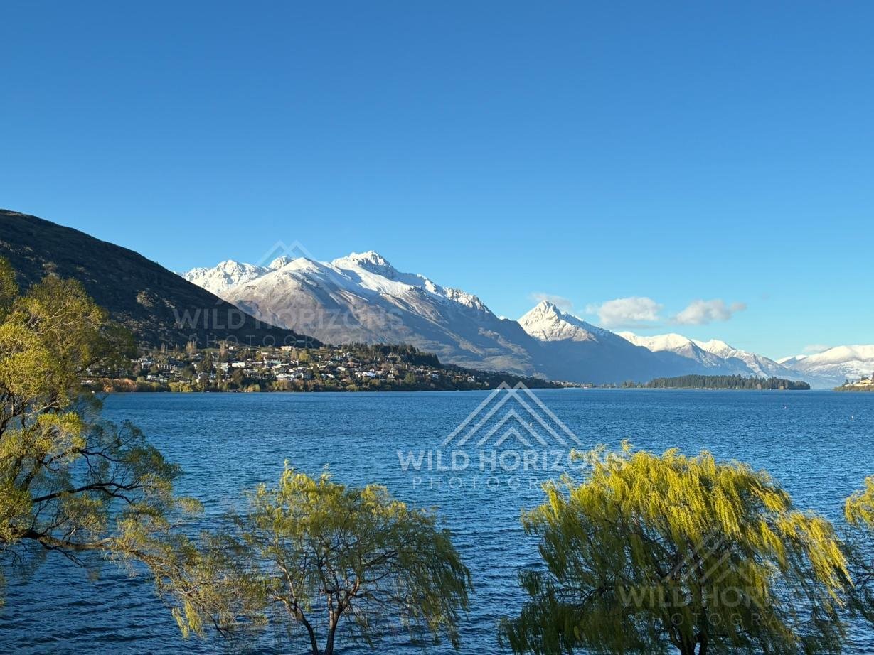 Still lake waters beneath snow-lined alpine ridges. Frankton, New Zealand