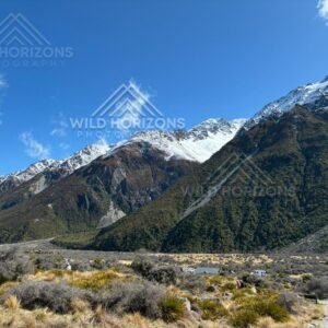 Alpine valley floor beneath steep snow-dusted mountain slopes. Aoraki / Mount Cook National Park, New Zealand