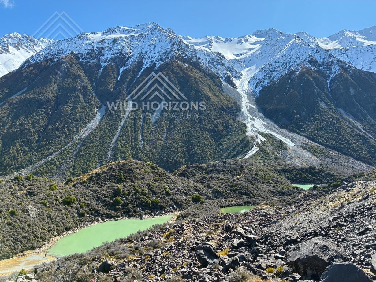 Glacial lakes beneath steep avalanche-carved alpine slopes. Aoraki / Mount Cook National Park, New Zealand