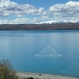 Wide alpine lake under layered cloud formations. Mackenzie Basin, New Zealand