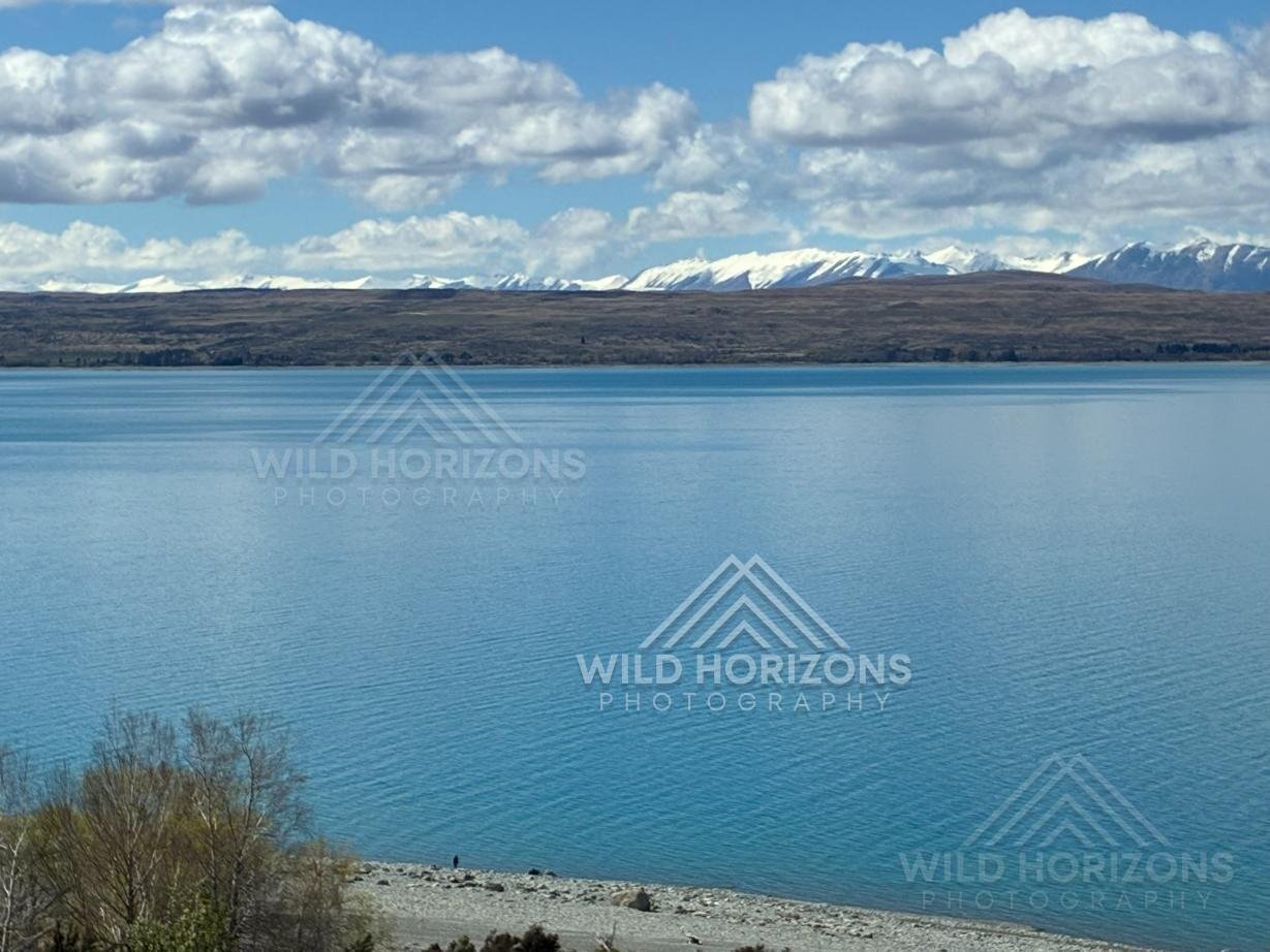 Wide alpine lake under layered cloud formations. Mackenzie Basin, New Zealand