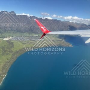 Aircraft wing frames an aerial view across Lake Wakatipu and Queenstown. Queenstown and Lake Wakatipu, New Zealand