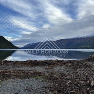 Rocky lakeshore and distant mountains reflected on the still surface of Lake Te Anau. Lake Te Anau, New Zealand