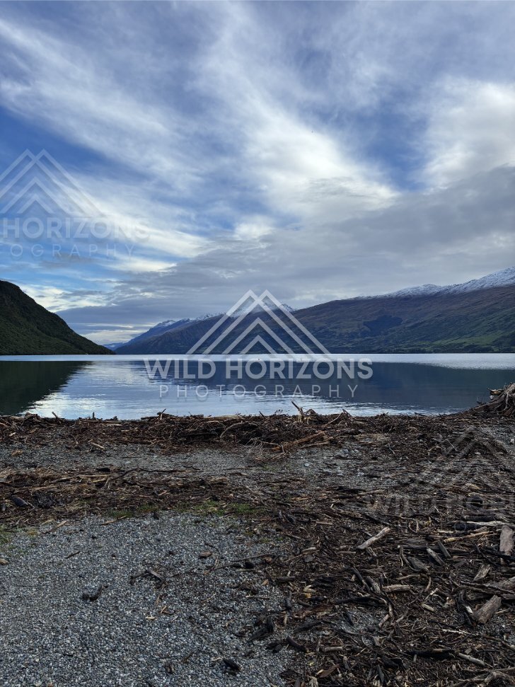 Rocky lakeshore and distant mountains reflected on the still surface of Lake Te Anau. Lake Te Anau, New Zealand