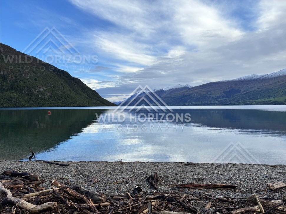 Wide view across the glassy waters of Lake Te Anau toward forested slopes and peaks. Lake Te Anau, New Zealand