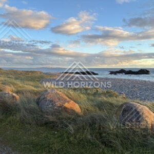 Golden Light on Coastal Boulders and Wind-Brushed Dunes Beside a Rocky Shoreline. Riverton, New Zealand