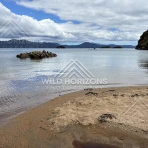 Gentle Lapping Water and a Rocky Islet Seen from a Small Sandy Point. Ulva Island, New Zealand