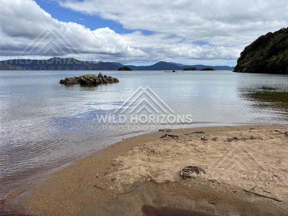 Gentle Lapping Water and a Rocky Islet Seen from a Small Sandy Point. Ulva Island, New Zealand