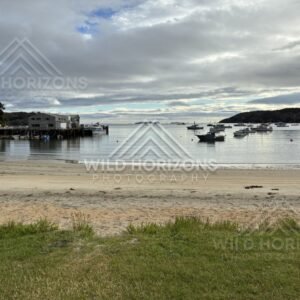 Quiet beach and moored boats in the township harbour. Oban, Stewart Island, New Zealand