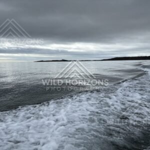 Boat wake cutting through calm inlet water under layered cloud. Paterson Inlet, New Zealand
