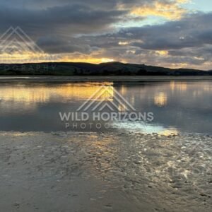 Dramatic cloud mirrored in shallow tidal water at dusk. Surat Bay, New Zealand