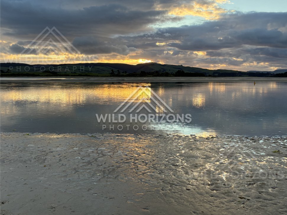 Dramatic cloud mirrored in shallow tidal water at dusk. Surat Bay, New Zealand