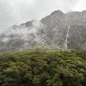 Multiple waterfalls on a Fiordland mountainside in rain on Milford Road, New Zealand