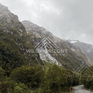 Winding mountain road beneath waterfalls on Milford Road, New Zealand