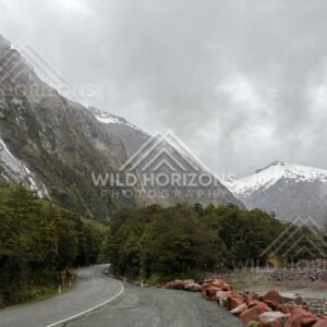 Wet highway and snow-capped peaks on Milford Road, New Zealand