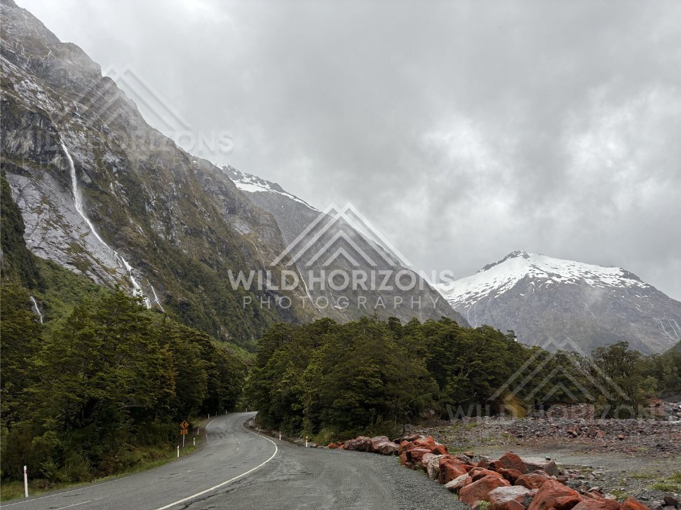 Wet highway and snow-capped peaks on Milford Road, New Zealand