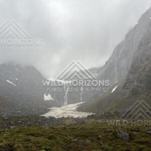 Alpine basin with snowfield and falls on Milford Road, New Zealand