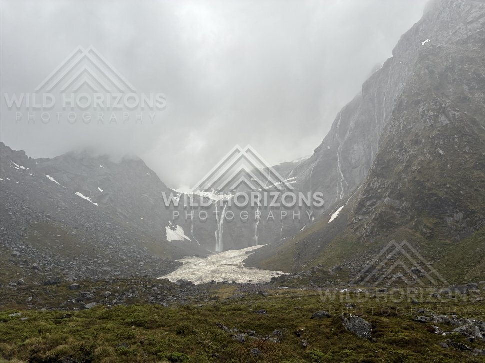 Alpine basin with snowfield and falls on Milford Road, New Zealand
