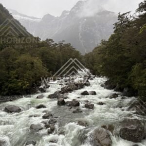 Boulder-strewn river rapids beneath misty peaks, Milford Road, New Zealand