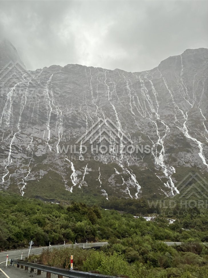 Milford Road beneath a wall of rain-fed waterfalls, New Zealand