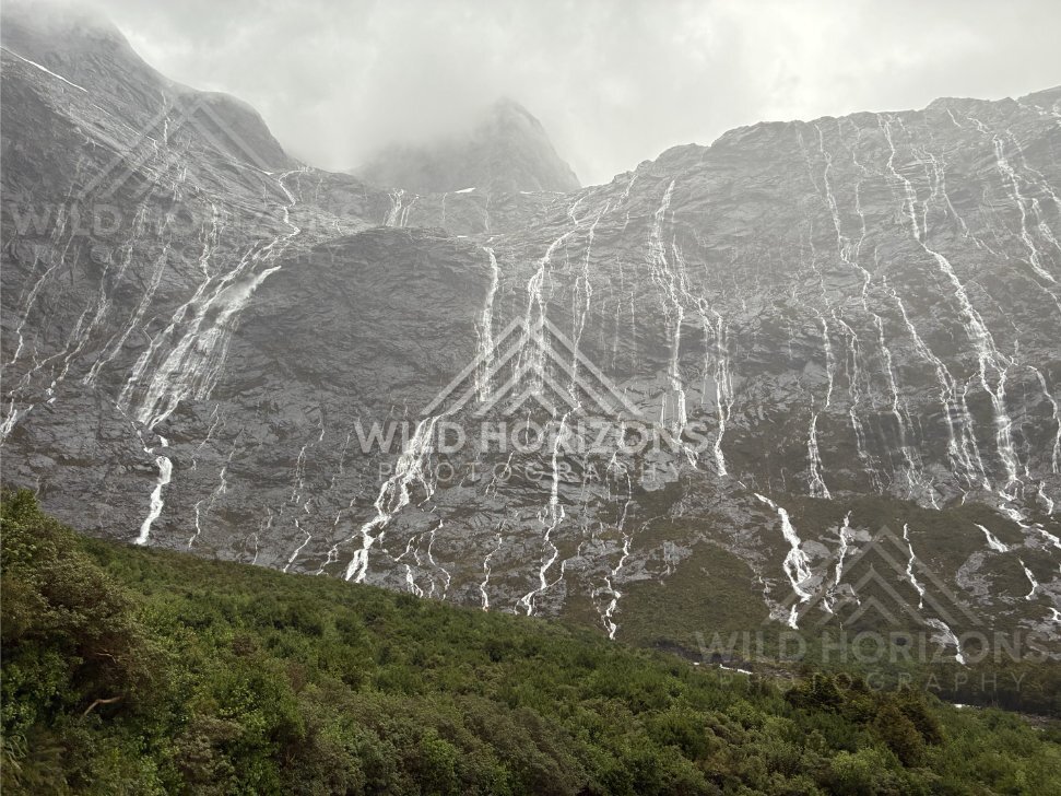 Waterfall-laced cliffs under low cloud, Milford Road, New Zealand