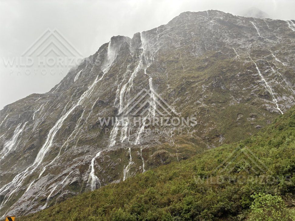 Steep Fiordland escarpment with multiple waterfalls, Milford Road, New Zealand
