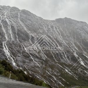 Milford Road switchback under waterfall-covered cliffs, New Zealand