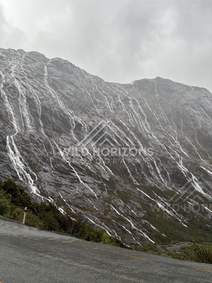 Milford Road switchback under waterfall-covered cliffs, New Zealand