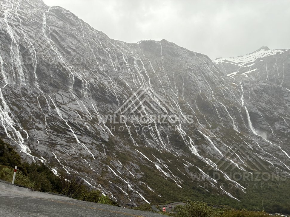 Waterfall-streaked mountains and winding road, Milford Road, New Zealand