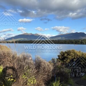 Fiordland lake and mountains under bright clouds, Milford Road, New Zealand