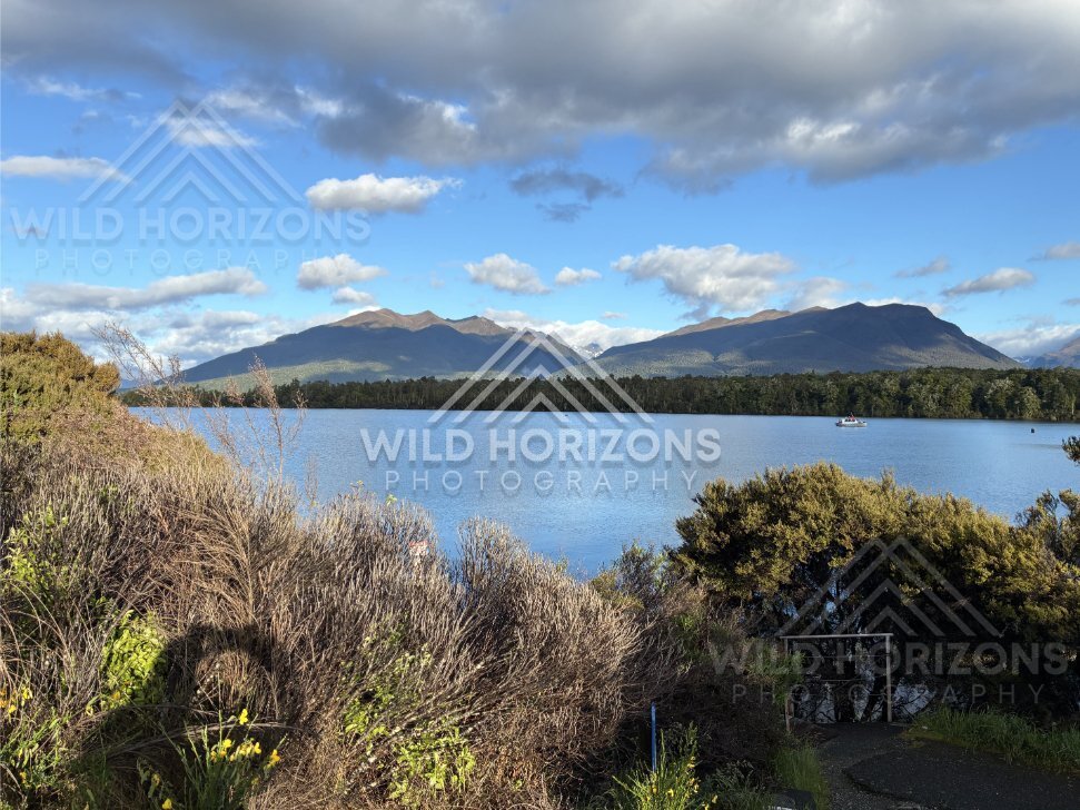 Fiordland lake and mountains under bright clouds, Milford Road, New Zealand