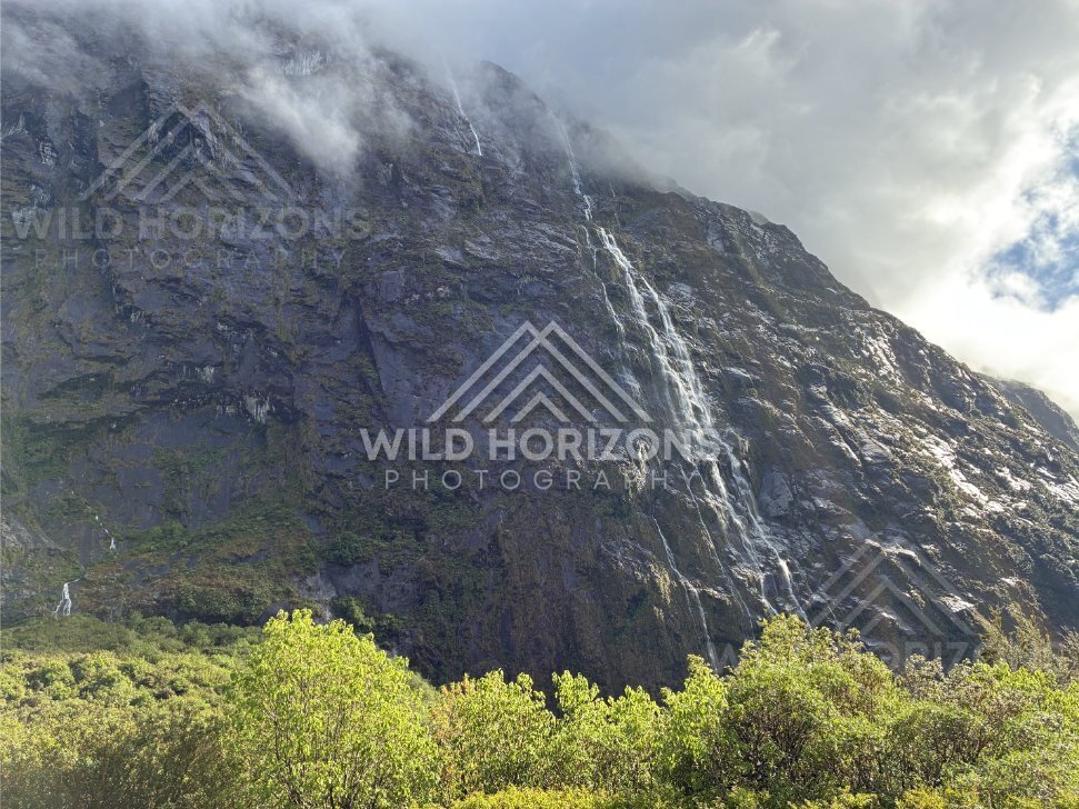 Sunlit Fiordland Waterfall on a Slanted Rock Face, Milford Road, Fiordland National Park, New Zealand
