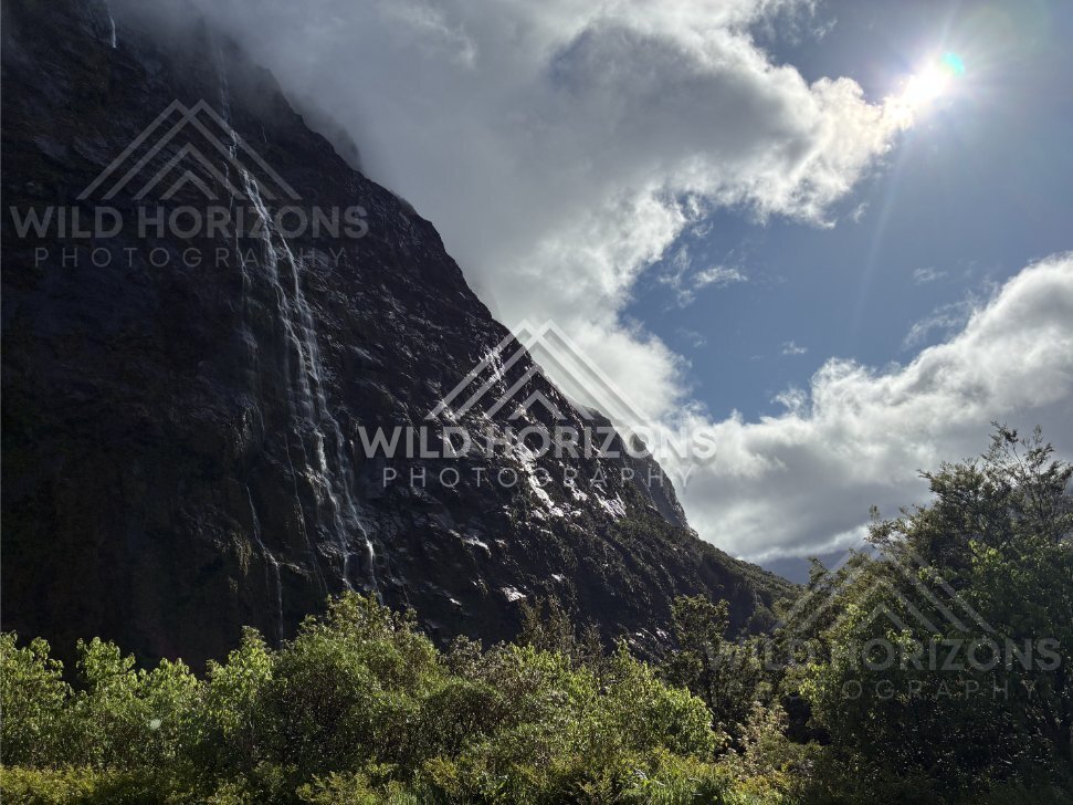 Waterfall and Sunburst over Fiordland Mountains, Milford Road, Fiordland National Park, New Zealand