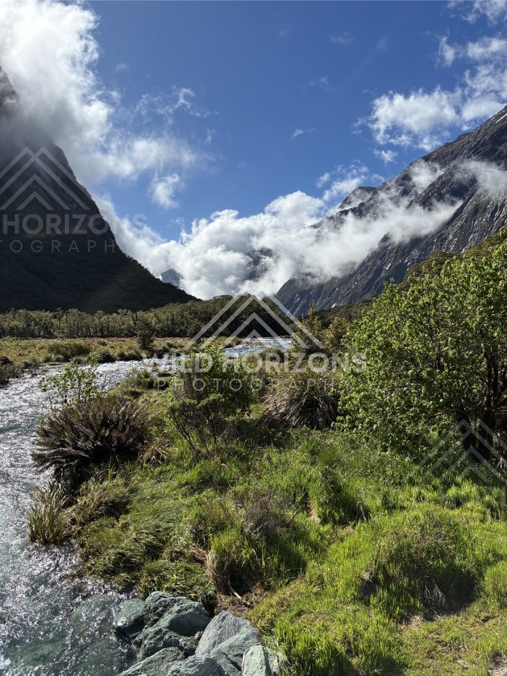 Sunlit Riverbank with Clouds in a Fiordland Valley, Milford Road, Fiordland National Park, New Zealand