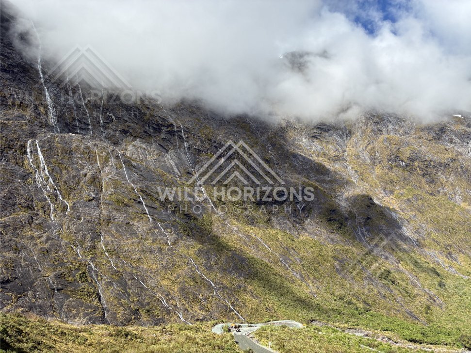 Winding Milford Road Under Cloudy Peaks and Waterfall Streaks, Milford Road, Fiordland National Park, New Zealand