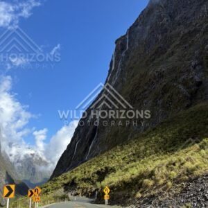 Curve Warning Signs on the Milford Road Below a Towering Waterfall, Milford Road, Fiordland National Park, New Zealand