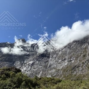 Sunlit Rock Face with Misty Cloud and Waterfall Threads, Milford Road, New Zealand