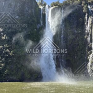 Towering waterfall with sunlit spray, Milford Sound, New Zealand