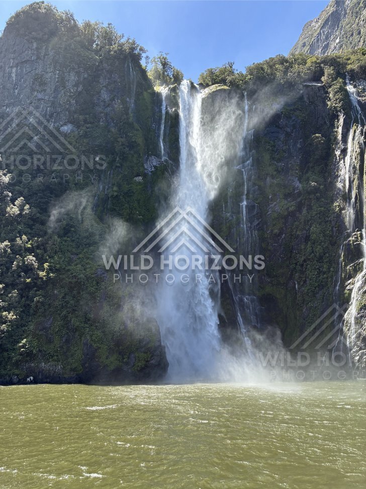 Towering waterfall with sunlit spray, Milford Sound, New Zealand