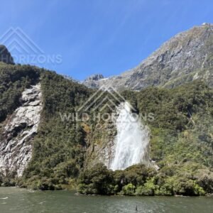 Waterfall spilling over bush-clad slope, Milford Sound, New Zealand