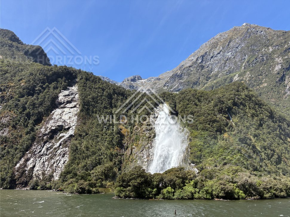 Waterfall spilling over bush-clad slope, Milford Sound, New Zealand