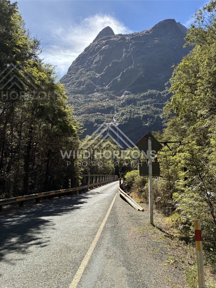 Forest road bridge beneath towering Fiordland mountain, Milford Road, New Zealand