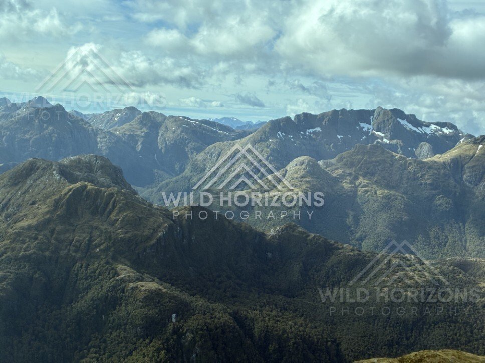 Layered mountain ranges beneath broken cloud. Fiordland, New Zealand.