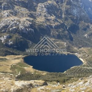 Tarn lake surrounded by rocky alpine slopes. Fiordland, New Zealand.