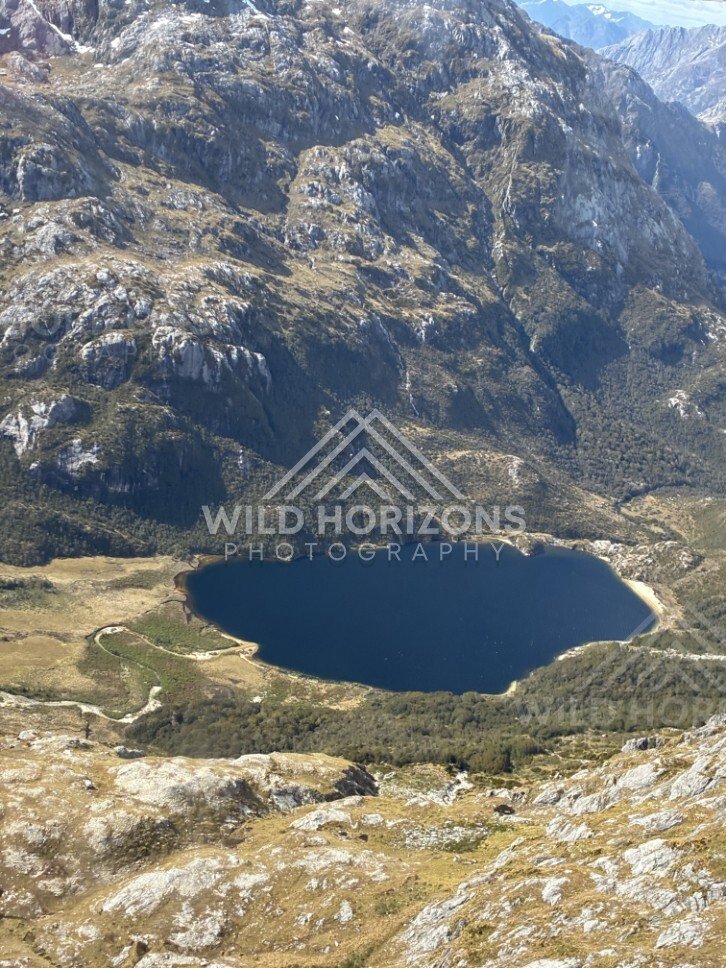 Tarn lake surrounded by rocky alpine slopes. Fiordland, New Zealand.
