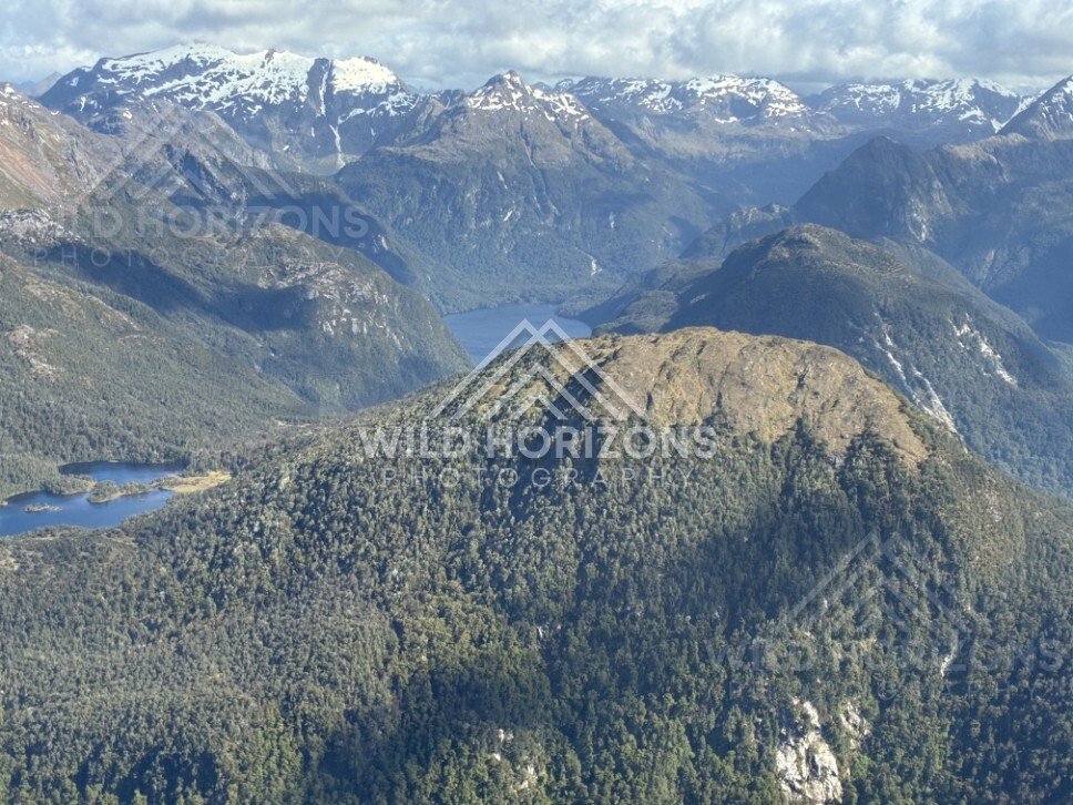 Sunlit ridgelines above layered Fiordland lakes. Fiordland, New Zealand.