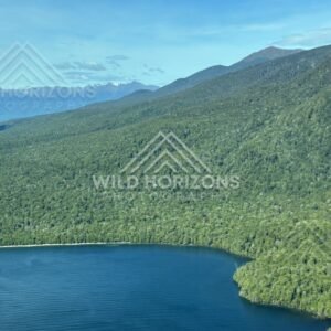 Forested peninsula extending into clear blue lake. Fiordland, New Zealand.