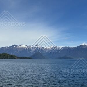 Calm lake with distant snow-dusted ranges. Manapouri, New Zealand.