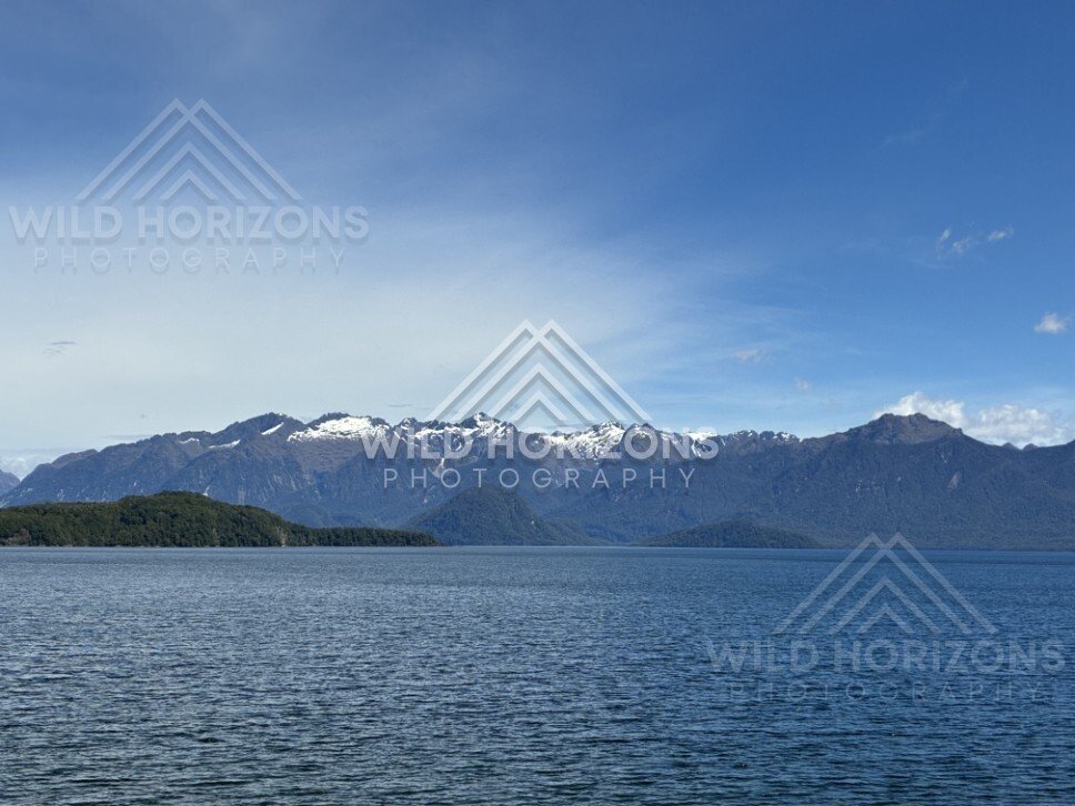 Calm lake with distant snow-dusted ranges. Manapouri, New Zealand.